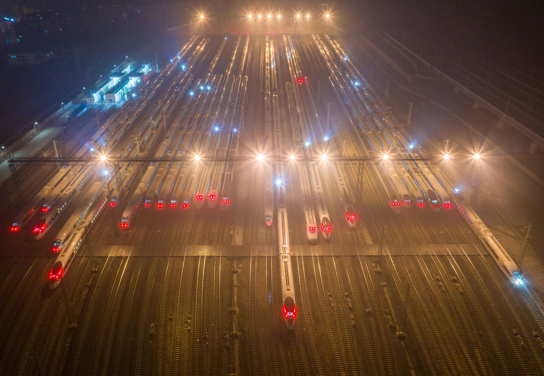 A nighttime aerial view of trains at an illuminated railway station in Nanjing, China.
