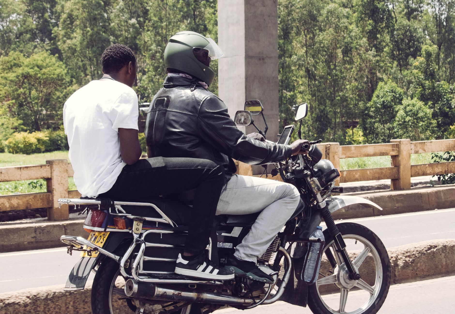 Two men on a motorcycle ride through Nairobi, showcasing urban transport and lifestyle.