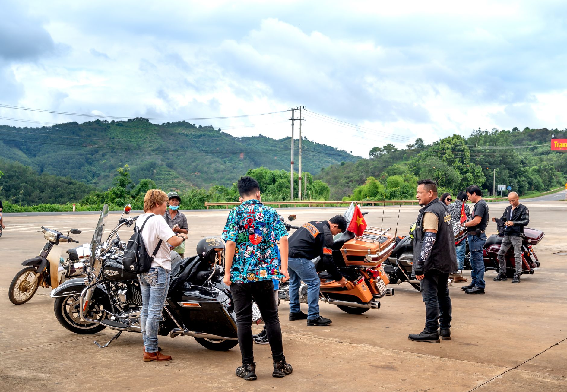 Group of bikers gathered at a scenic outdoor location with motorcycles parked.
